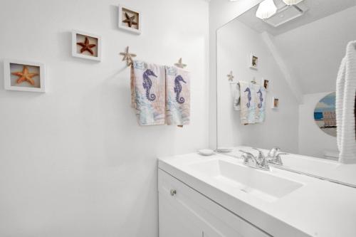 a white bathroom with a sink and a mirror at Sandcastles and Sunshine - Gulf Highlands Beach Resort in Panama City Beach