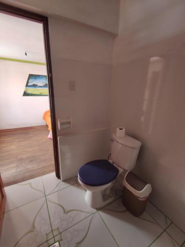 a bathroom with a toilet with a blue seat at Hostal Margarita in Comunidad Challapampa