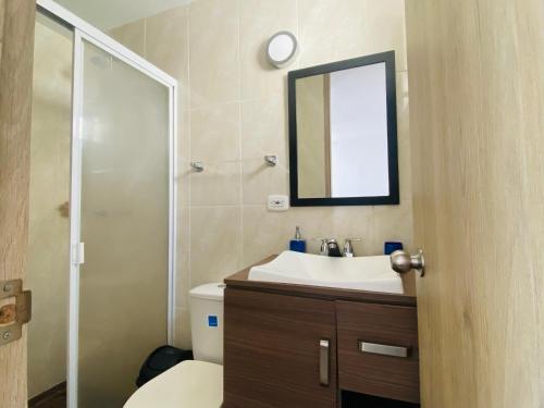 une salle de bain avec toilettes, lavabo et miroir dans l'établissement Apartamento en Ricaurte - Reserva de Peñalisa, à Ricaurte