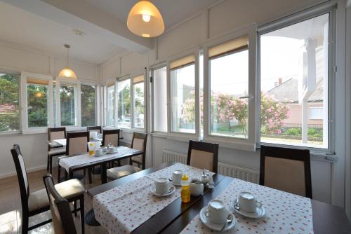 a restaurant with tables and chairs and windows at Wellness Hotel Kakadu in Keszthely