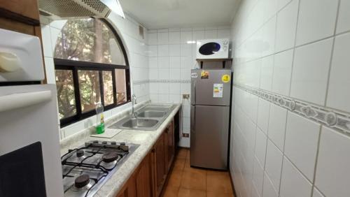 a small kitchen with a refrigerator and a sink at Casa encantadora con servicio de transporte al Aeropuerto in Osorno