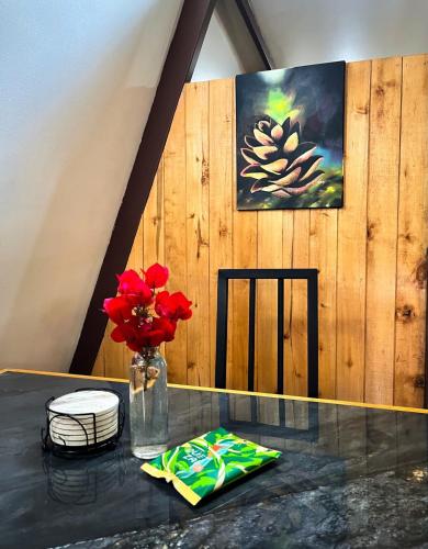 a table with a vase of flowers and a painting at Cabaña Azalea en Santa María de Dota in Santa María