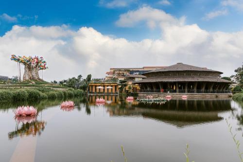 a large building with pink flowers in the water at Hoi An Memories Resort & Spa in Hoi An
