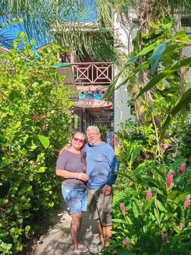 an older man and woman standing in front of a house at Hotel Capitan Playa Tela in Tela