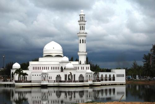 a white mosque with a tower on top of a lake at TY Hotel in Kuala Terengganu