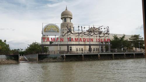 a building with a clock tower next to a body of water at TY Hotel in Kuala Terengganu