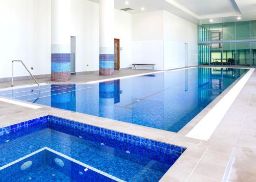 a large swimming pool with blue water in a building at Elegant Splendor 3 bedroom Apartment with Tram Access in Gold Coast