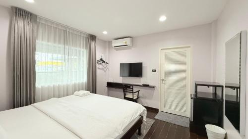 a bedroom with a bed and a desk and a television at Issara House Bangkok in Bangkok