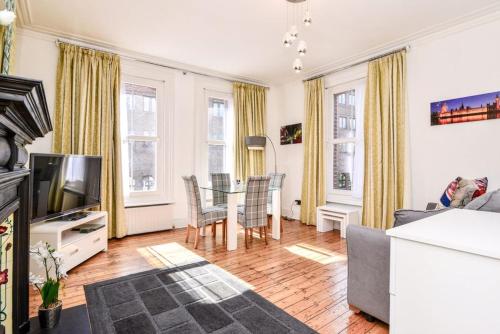 a living room with a table and chairs and a television at Gorgeous First Floor apartment near Station in London