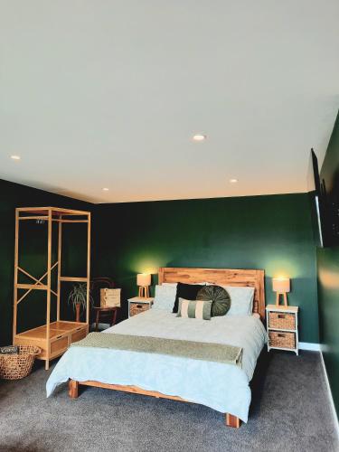 una camera da letto con un letto grande con una parete verde di Whakatā Place a Motueka
