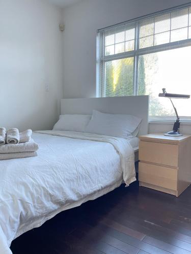 a bedroom with a bed and a lamp on a night stand at Cozy Guest Rooms Near UBC, Downtown and Beaches in Vancouver