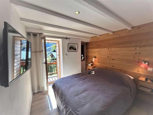 - une chambre avec un lit et un mur en bois dans l'établissement Maison atypique près télésiège, parking et fibre - FR-1-180-644, à Les Allues