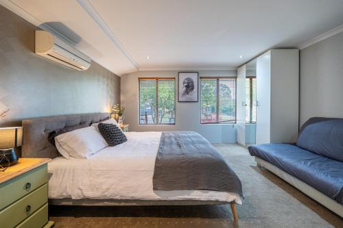 une chambre avec un lit et un canapé bleu dans l'établissement Airport 5BR Haven - Full Kitchen & Tranquil, à Perth