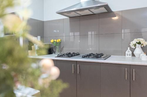 a kitchen with a stove and some flowers on the counter at Airport 5BR Haven - Full Kitchen & Tranquil in Perth