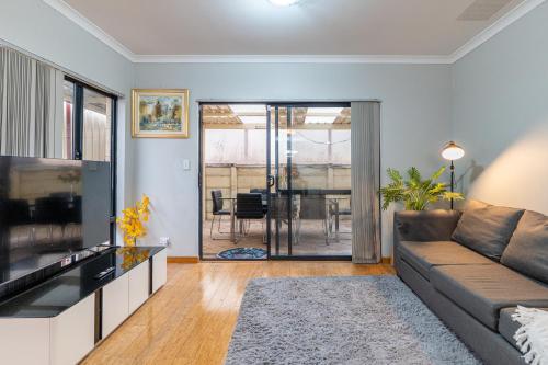 a living room with a couch and a table at Airport 5BR Haven - Full Kitchen & Tranquil in Perth