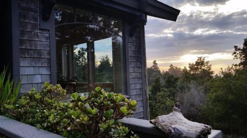 a house with a window with a view of the sunset at Amazing Getaway Oceanview with treehouse feel in Manchester