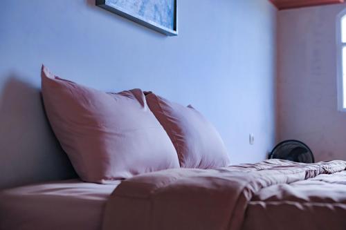 a bed with two pillows on top of it at Mahogany Garden Villa Jogja in Ngingas