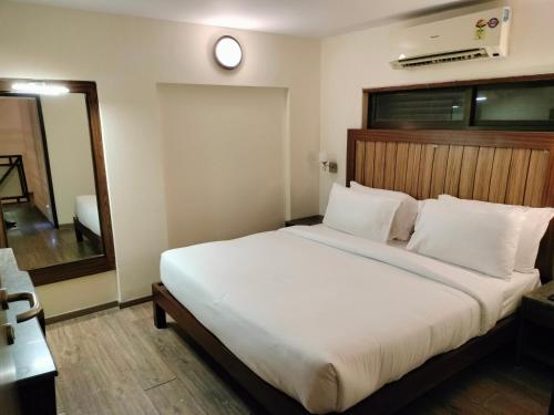 a bedroom with a large white bed with a mirror at VITS Lonavala in Lonavala