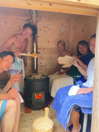 a group of people in a log cabin with a stove at 与論ゲストハウス ズッ友荘 in Furusato