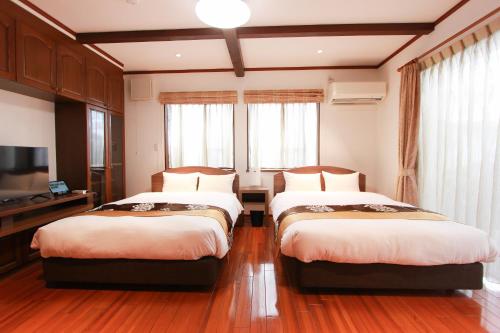 a bedroom with two beds and a television at HOTEL DO-YA BEPPU Bekkan in Beppu