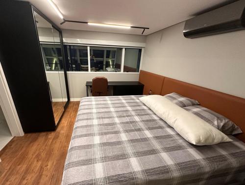 a bedroom with a bed with a plaid blanket at Loft Duplex com Hidromassagem in Florianópolis