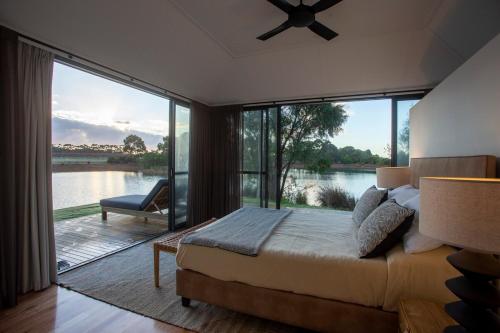a bedroom with a bed and a large glass window at Caves Road Vineyard Retreat in Wilyabrup