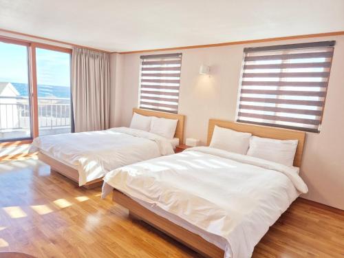 two beds in a room with two windows at Memories Hotel in Sokcho