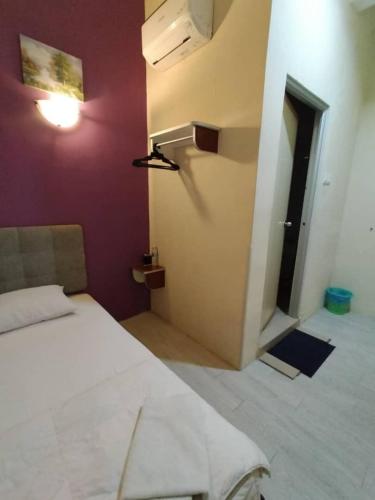 a bedroom with a white bed and a purple wall at Hotel Bestari in Melaka