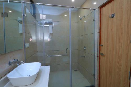 a bathroom with a glass shower and a sink at Country Green Hotel & Banquet in Bareilly