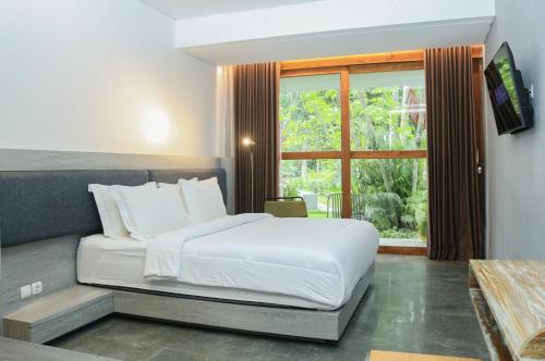 a bedroom with a white bed and a window at The Setumbu Experience, ARTOTEL Curated in Kembanglimus