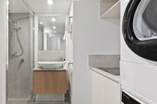a bathroom with a sink and a washing machine at Bokarina Beach Apartments, an Ascend Collection Hotel in Bokarina