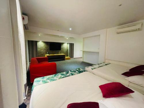 a hotel room with two beds and a red chair at The Grandeur in Melaka