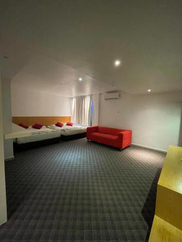 a room with two beds and a red couch at The Grandeur in Melaka