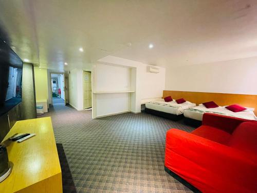 a hotel room with two beds and a red couch at The Grandeur in Melaka