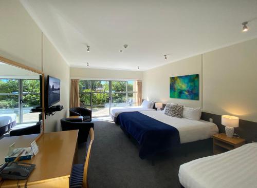 a hotel room with two beds and a desk at Saxton Lodge in Nelson