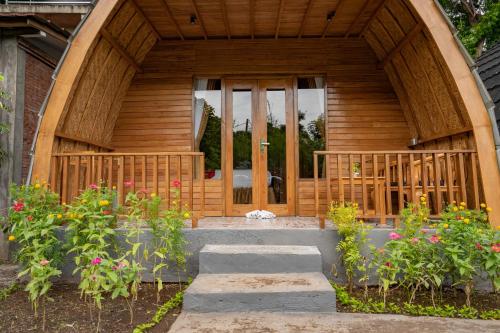 a wooden house with a wooden door and some flowers at Taman Bidadari Eco Wellness in Pemuteran
