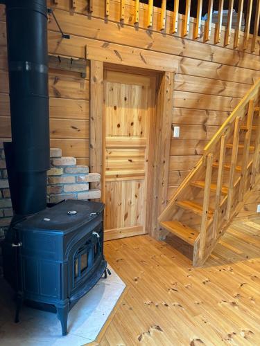 a log cabin with a stove and a staircase at SAUNA Log Cabin オーガスタハウス君津 in Kimitsu