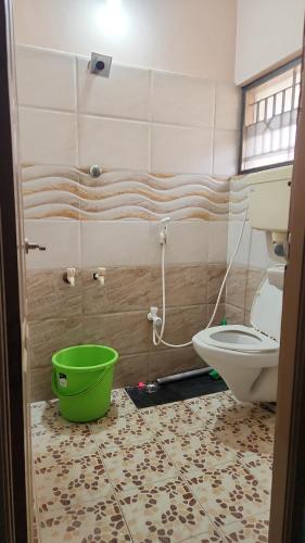 a bathroom with a toilet and a green bucket at Holiday Home Madurai Bharathi Nagar - FF in Tallākulam