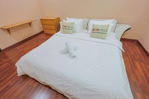 a white bed with two pillows and a cross on it at Spacious 12 pax Landed Homestay By NexxField in Ampang