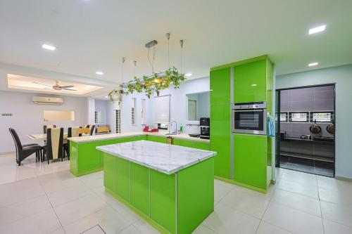 a kitchen with green cabinets and a dining room at Spacious 12 pax Landed Homestay By NexxField in Ampang