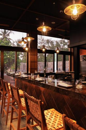 a restaurant with a bar with wooden chairs and windows at Hotel Indigo Bintan Lagoi Beach by IHG in Lagoi