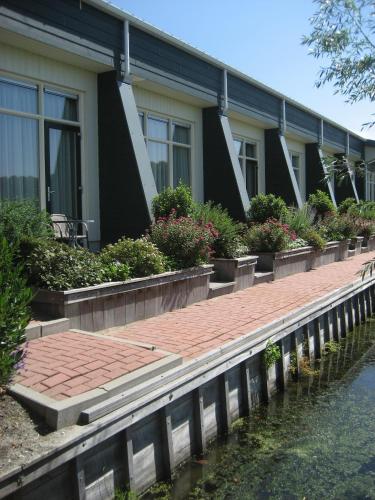 a house with a brick walkway next to the water at Hotel Beemster in Middenbeemster