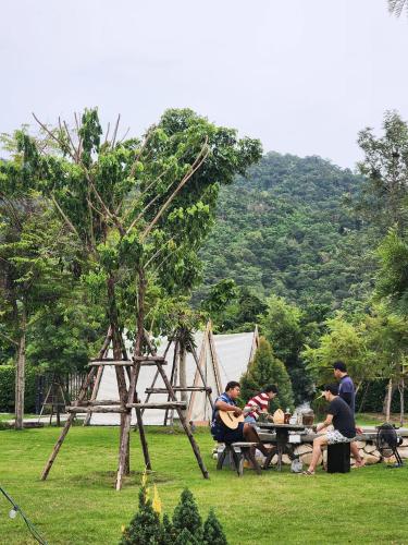a group of people sitting at a picnic table in the grass at Take Time Nature Resort in Ban Tha Sai