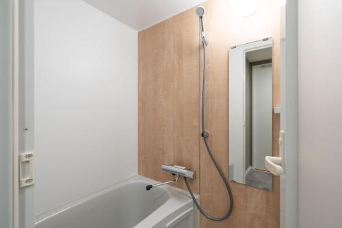 a bathroom with a tub and a shower with a mirror at High Leaf Shiba Daimon in Tokyo