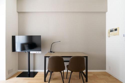a dining room table with two chairs and a television at High Leaf Shiba Daimon in Tokyo