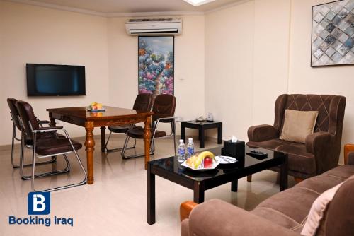 a living room with a couch and chairs and a tv at Andalus Hotel in Baghdad