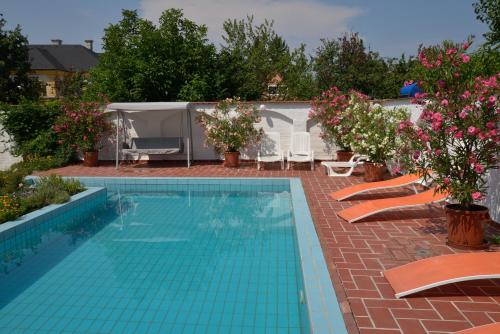 a swimming pool with chairs and flowers in a yard at Wellness Hotel Kakadu in Keszthely