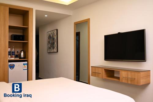 a bedroom with a bed and a television on a wall at Andalus Hotel in Baghdad