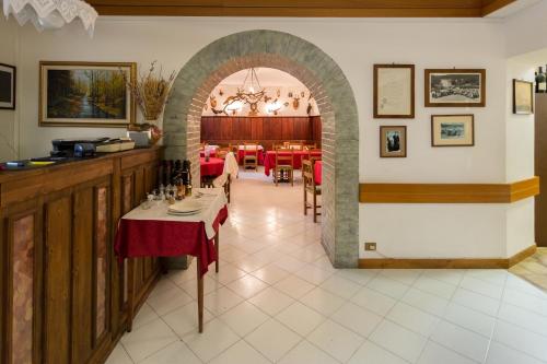 una sala da pranzo con arco e tavoli e sedie rossi di Hotel Krizman a Monrupino