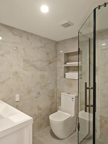 a bathroom with a toilet and a glass shower at Sunny Nook in Auckland